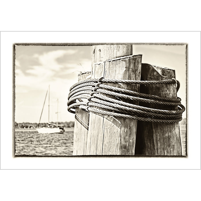 Image of Dockside mixed media sepia tone artwork by Jessica St. Clair depicting wood pilings and a sailboat at sea