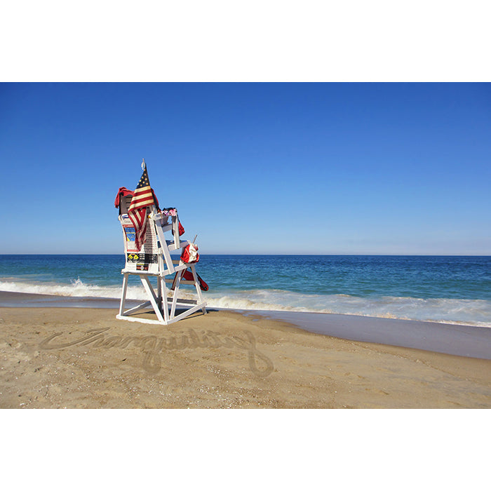 Image of Tranquility photographic artwork by Jessica St. Clair depicting a lifeguard stand with an American flag overlooking calm ocean water with the word tranquility written in the sand