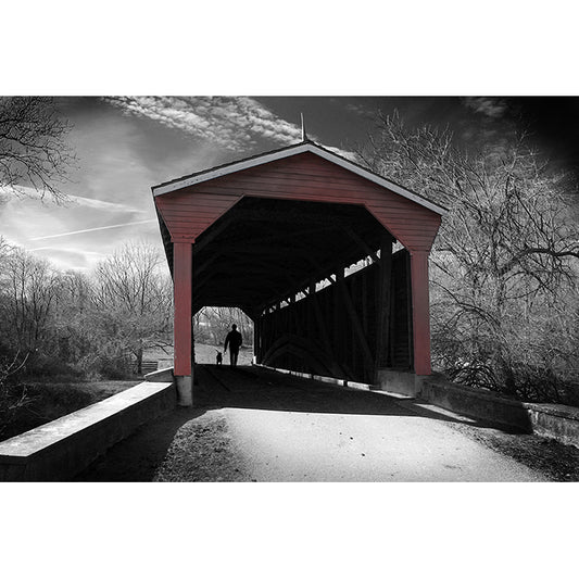 Image of Winter in Fair Hill artwork depicting a black and white winter scene with a man and dog in silhouette walking through a red covered bridge, by Jessica St. Clair.