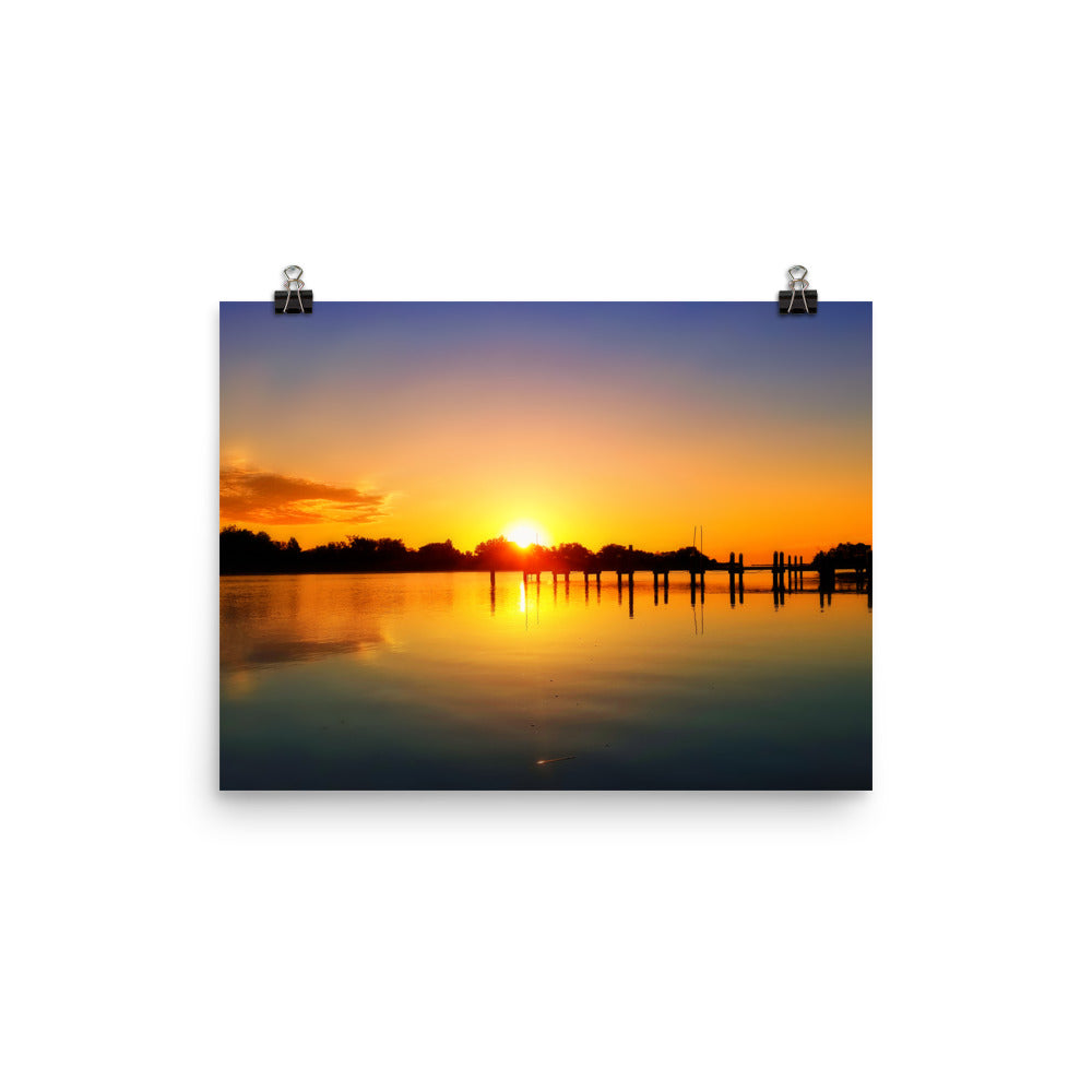 Image of Morning Majesty photographic art print on 12 inch by 16 inch premium luster photo paper by Jessica St. Clair depicting a colorful sunrise over a silhouetted dock stretching across the water