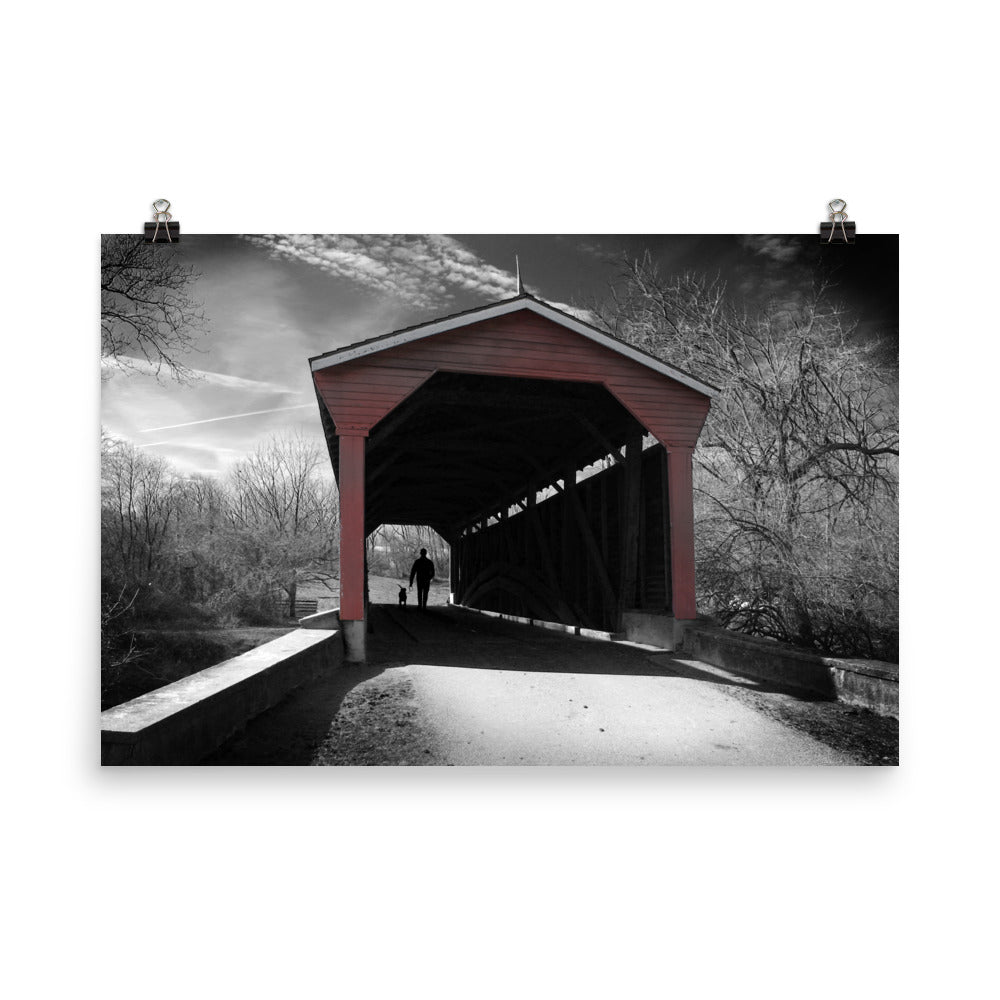 Image of Winter in Fair Hill 24 inch by 36 inch art print depicting a black and white winter scene with a man and dog in silhouette walking through a red covered bridge.